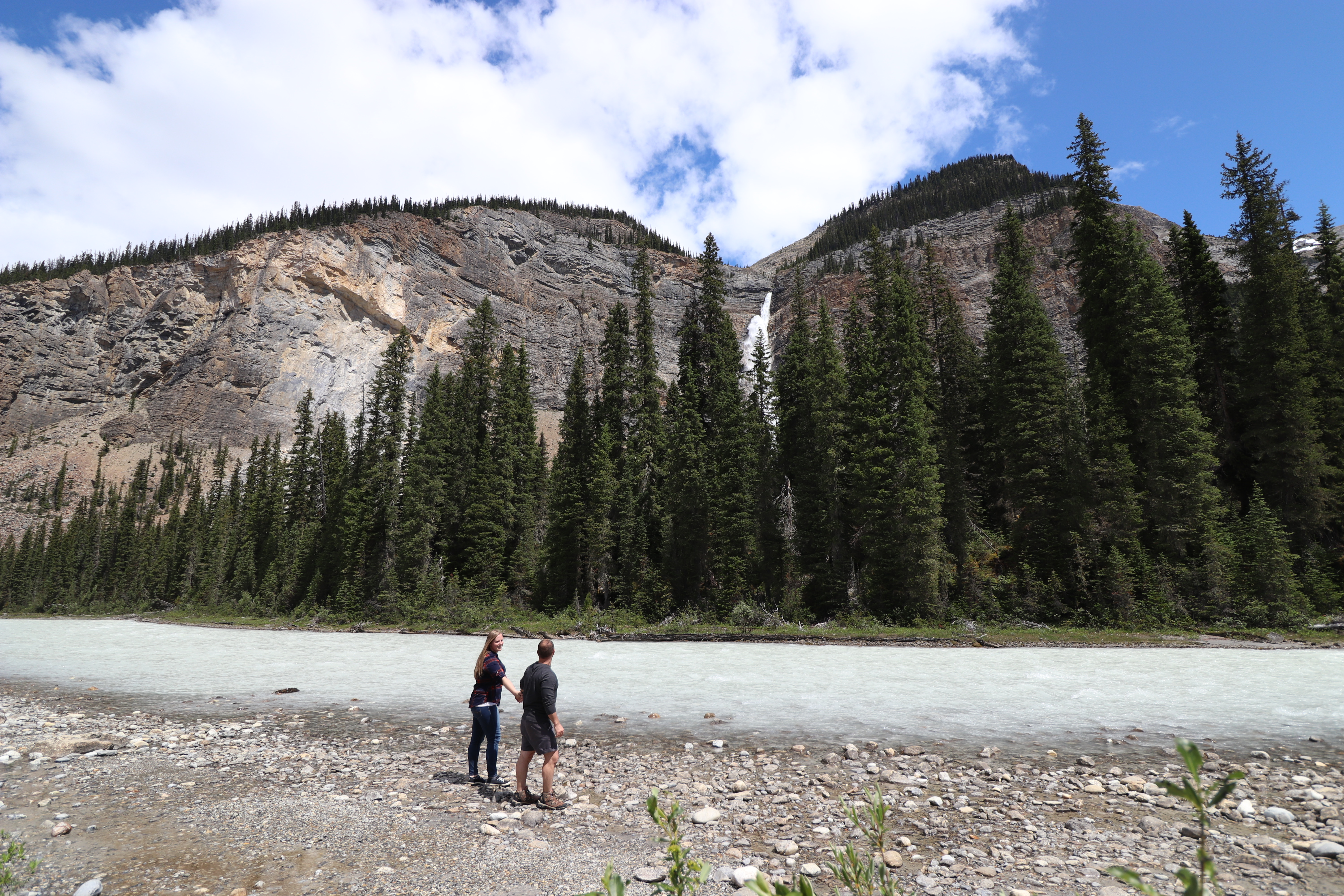 Emily and Mike of Traveling Twogether Stand in front of the grandeur Takakkaw Falls, British Columbia, Canada